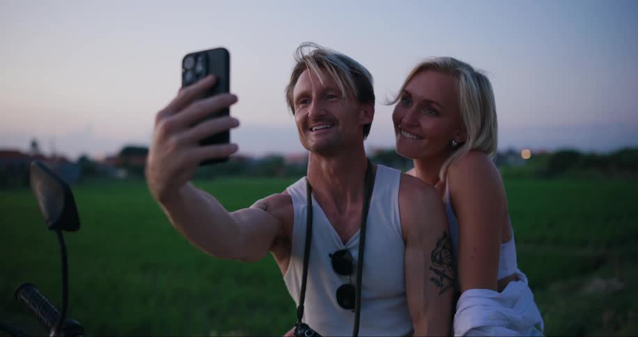 Couple sitting on a motorcycle and talking in selfie on a smartphone