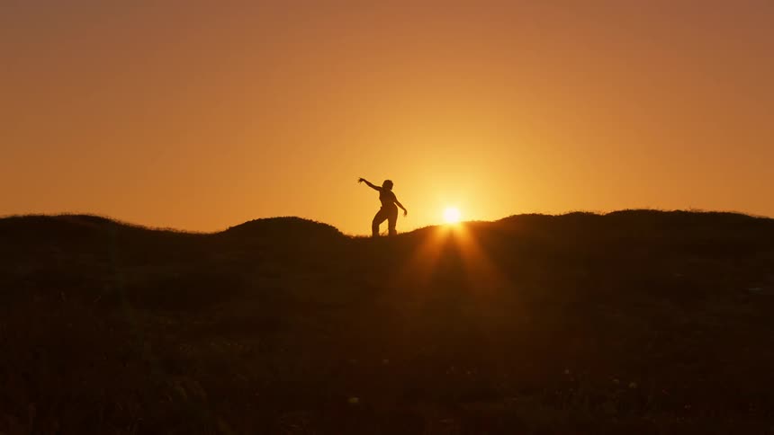 An individual doing yoga silhouetted by the setting or rising sun