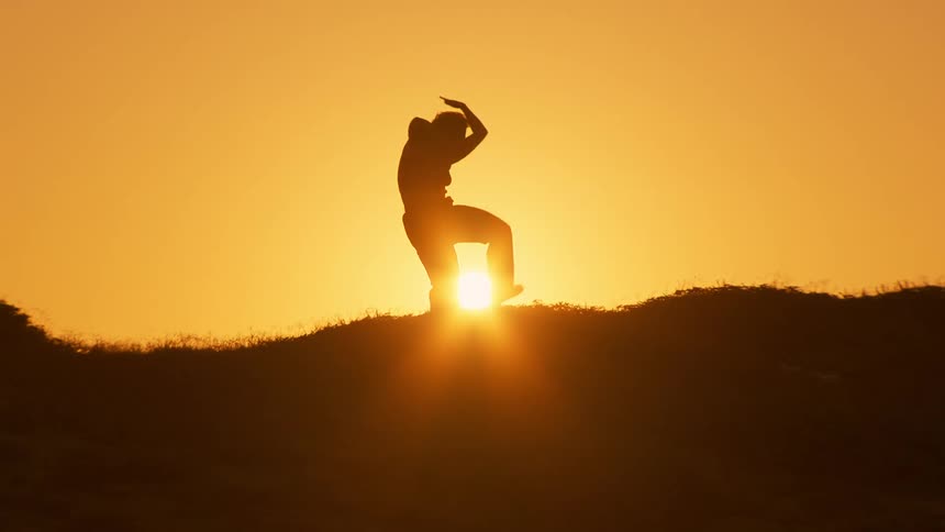Woman moves through various poses while silhouetted by the setting sun