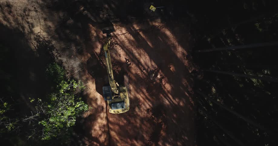 Aerial view of an excavator in a natural environment with trees around