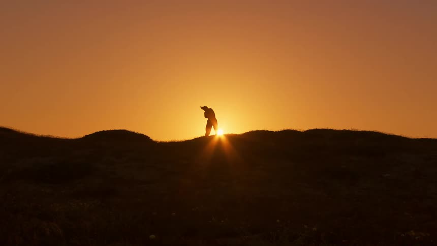 Silhouette of a person against a sky and an orange sun doing a tachi movement