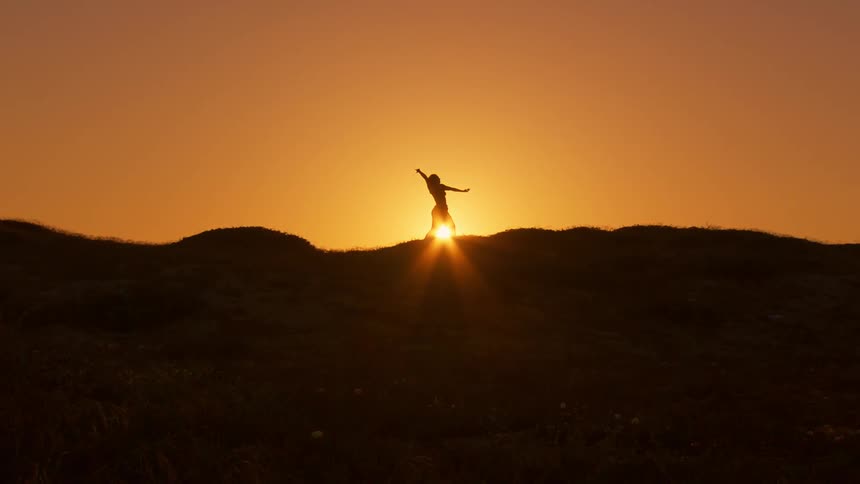 A silhouette of a person doing martial movements and behind the door sunlight and a very orange sky