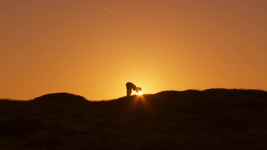 A person stretches on top of a mountain