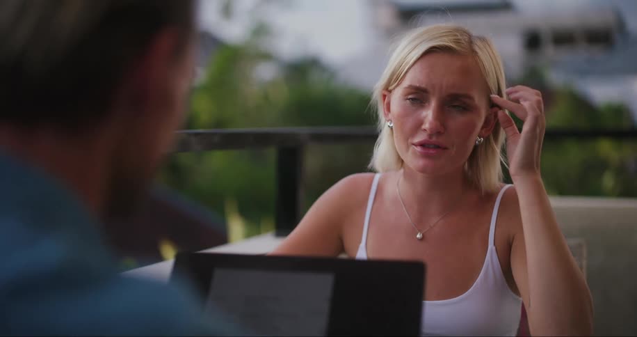 Man and woman sitting at a table with a laptop talking