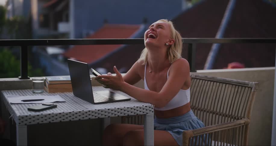 A woman laughs as she looks on her cell phone