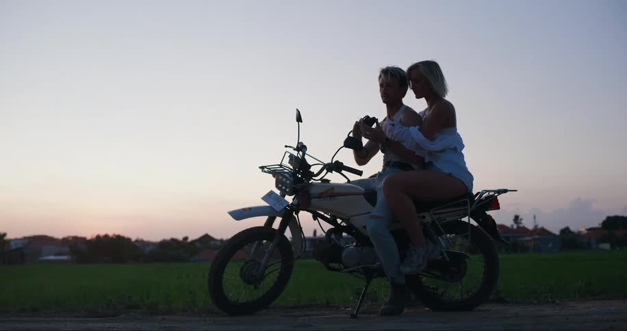 Man and woman sitting on a motorcycle holding each other romantically