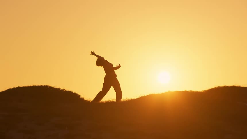 A woman stretches while standing on a grassy area