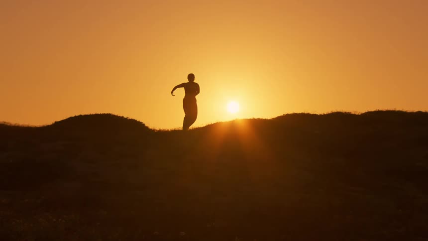 A person performs stretches on a grassy area