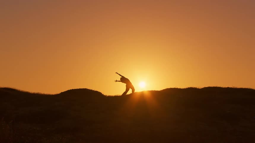 A woman does stretching on a grassy hilly area