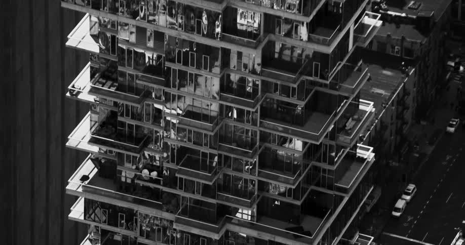 Reflective facade of apartment building towering over nearby intersection shimmers and shines
