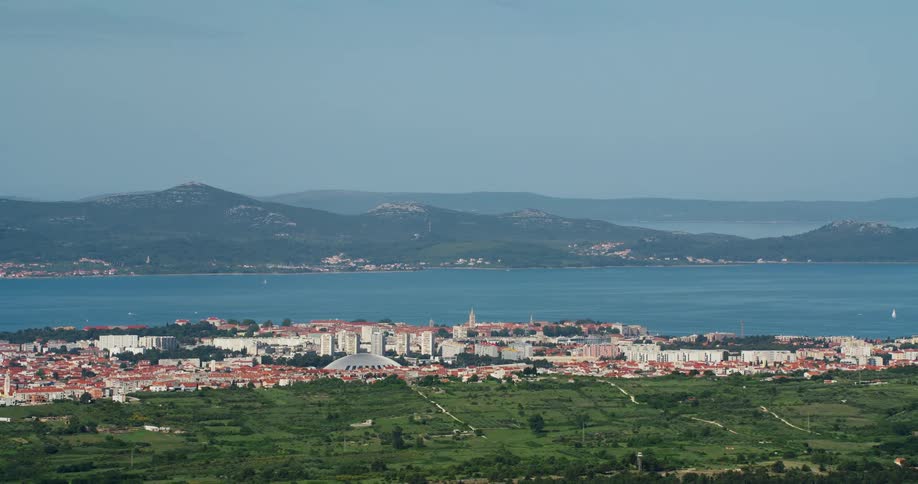 Aerial panorama of a city by the sea with the silhouette of mountains on the horizon