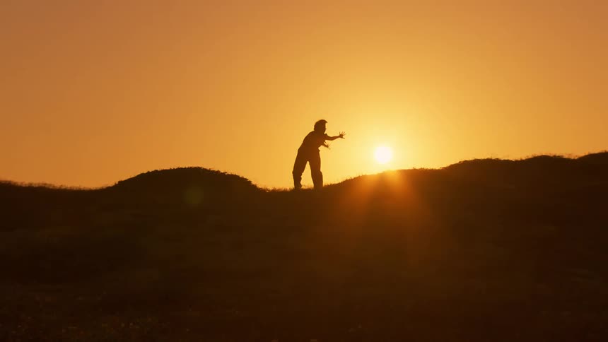 A woman dancing on a hills ridge at sunrise
