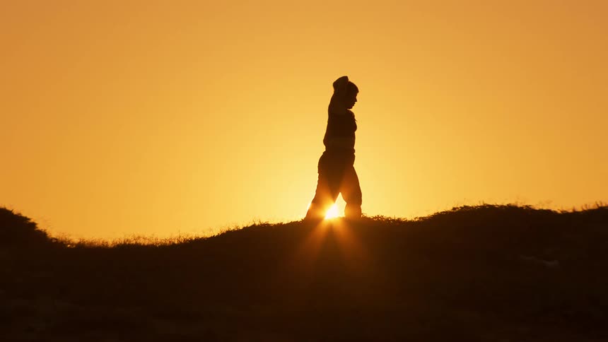 A woman is practicing tai chi at sunrise