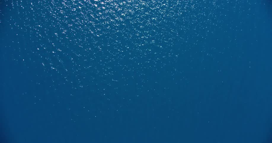 Aerial panorama of an expanse of blue ocean with sunlight reflection
