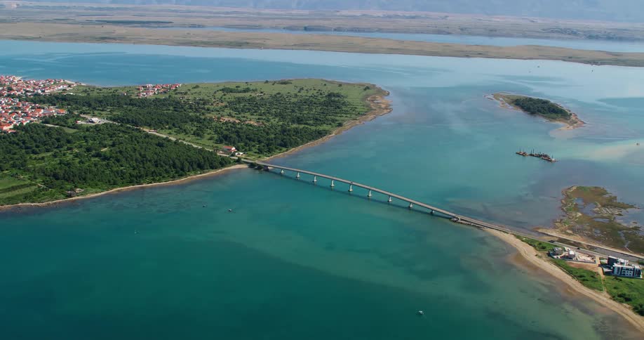 Bridge connects town on forested island to coastal area with foggy mountains in the background