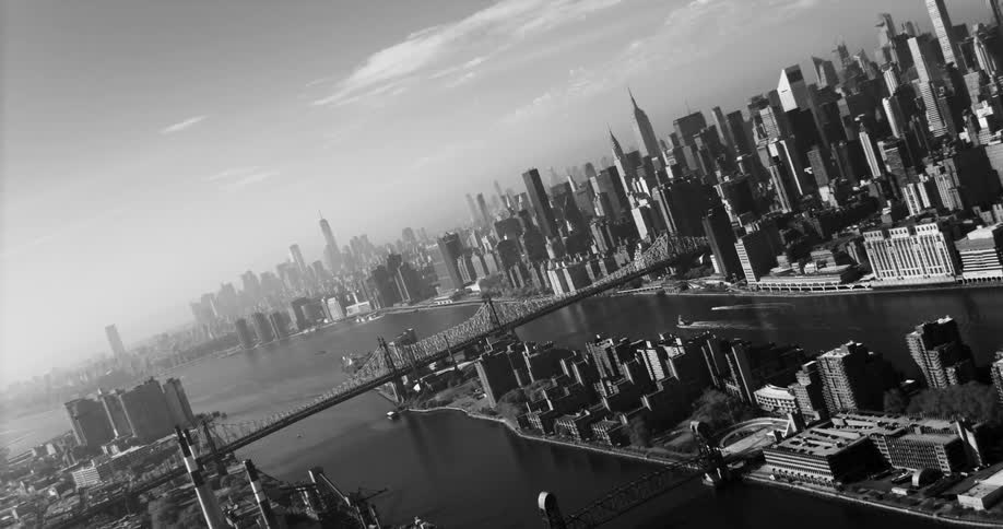 An aerial view of a metropolitan city with a huge suspension bridge over the water connecting two regions
