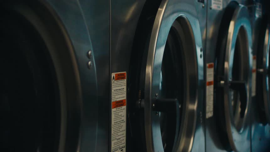 Man opens one of the machines in the laundromat