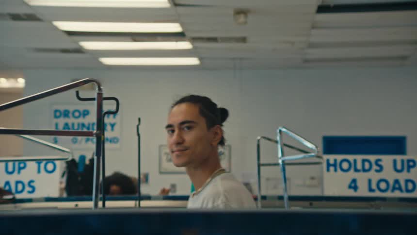 A man smiles as he walks through the laundromat