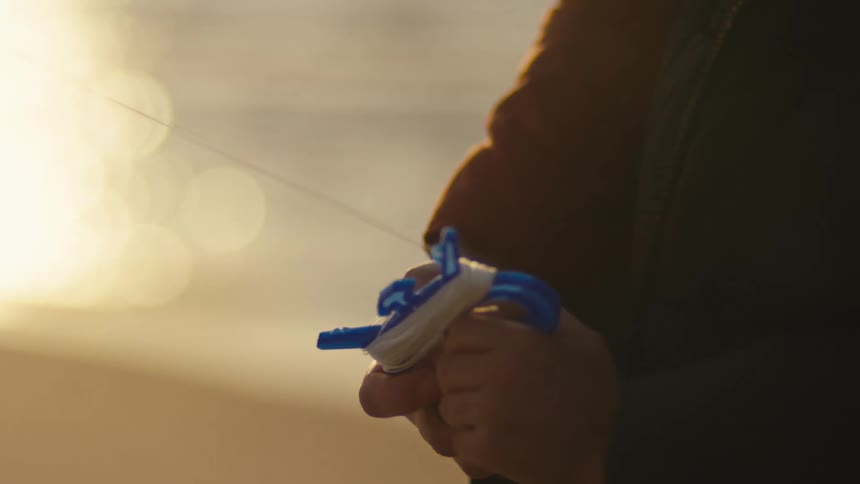 A childs hands holding the cord for a kite on a beach