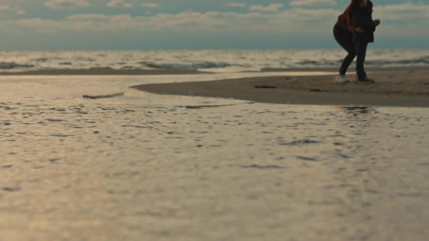 A woman helping a young boy fly a kite on a beach