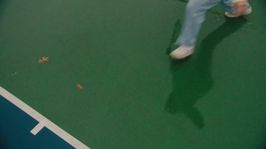 Legs of a person running on a wet tennis court
