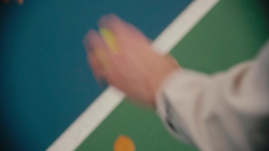 A tennis player swinging a racket at a yellow ball bouncing it