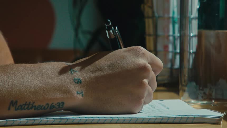 A man is writing in a notebook with his pen