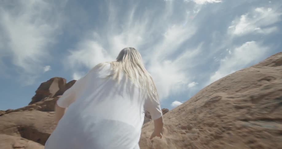 A woman runs and climbs through the desert