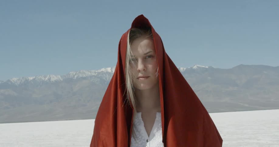 Woman standing outside in wilderness with red shawl over her head