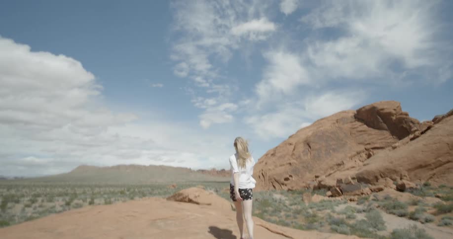 Woman running on large bald rock formations on windy day