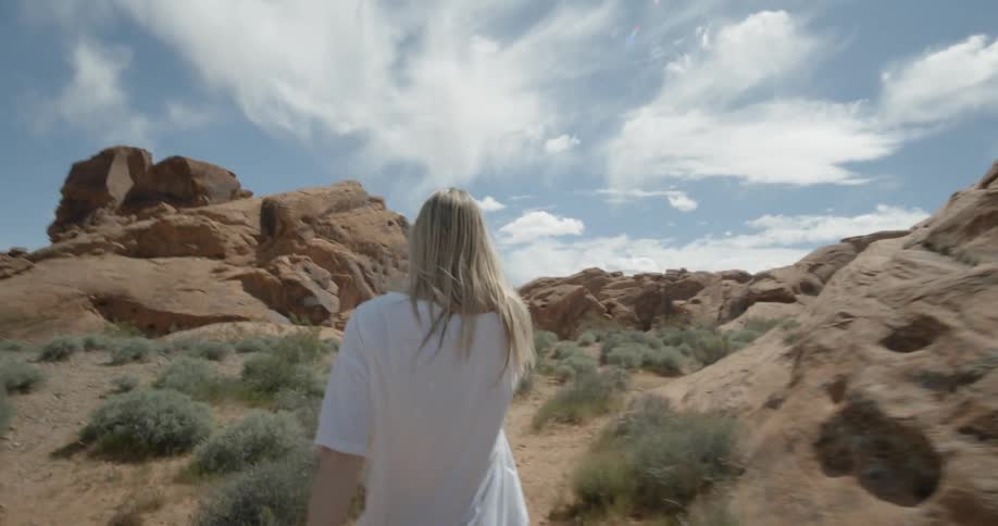 A woman walks through a valley