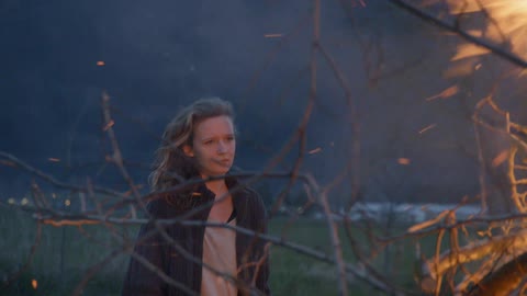 Sad girl standing close to a large bonfire