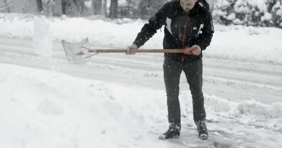 A man is shoveling outside as it snows