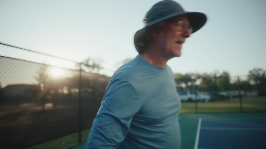 A man cracks a smile after hitting a pickleball on a court