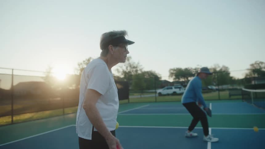 Older people play pairs pickle ball on a tennis court