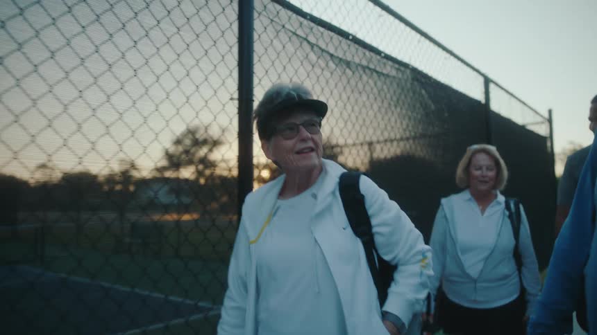 A group of elderly friends walking to the tennis court to play pickleball