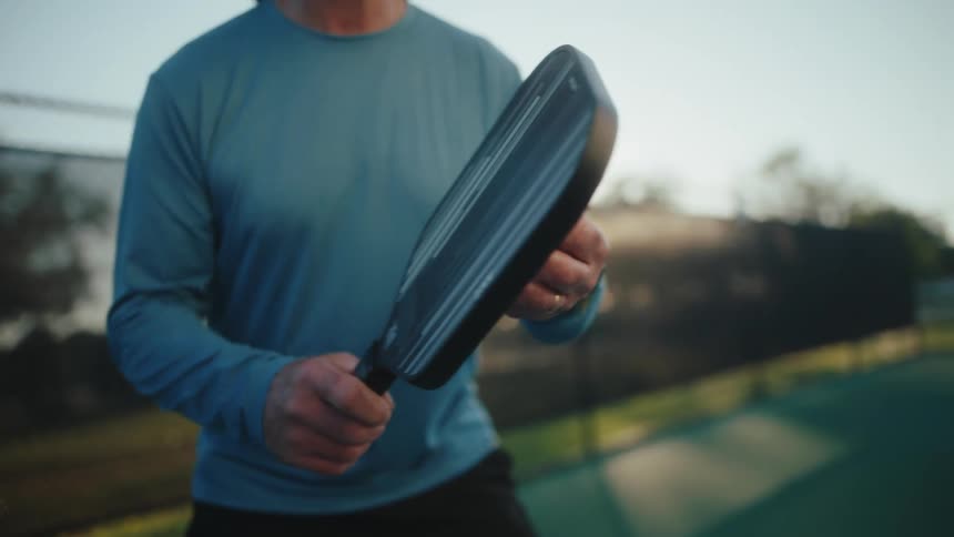 Person holding a pickleball paddle on a court