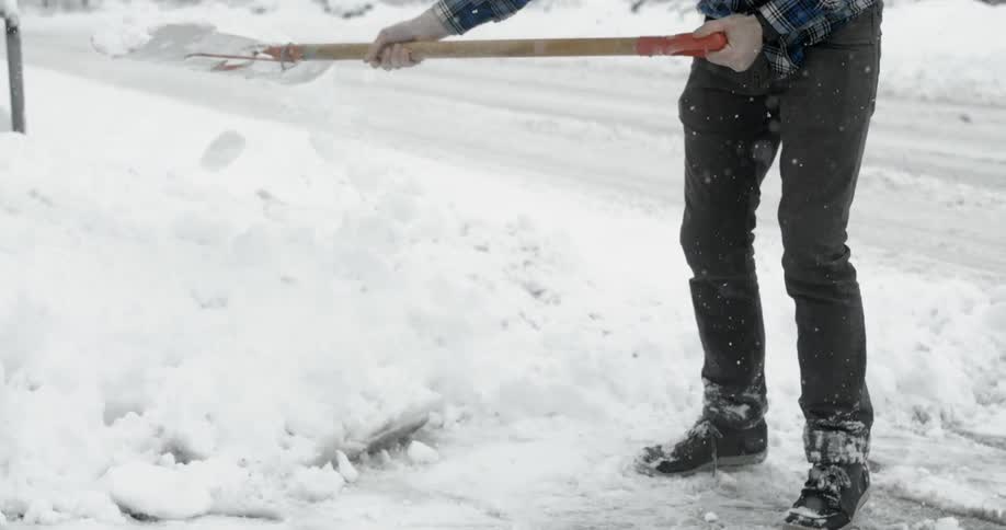 A man is shoveling snow on a snowy day