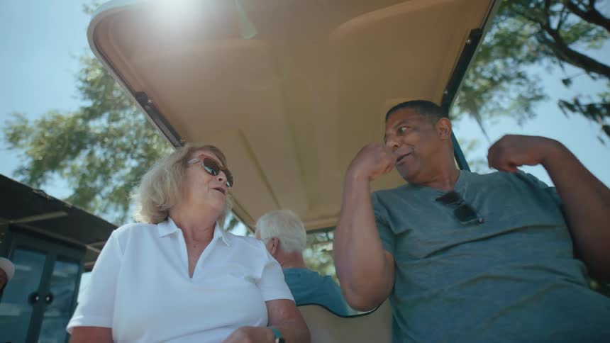 Four people in a golf cart talking