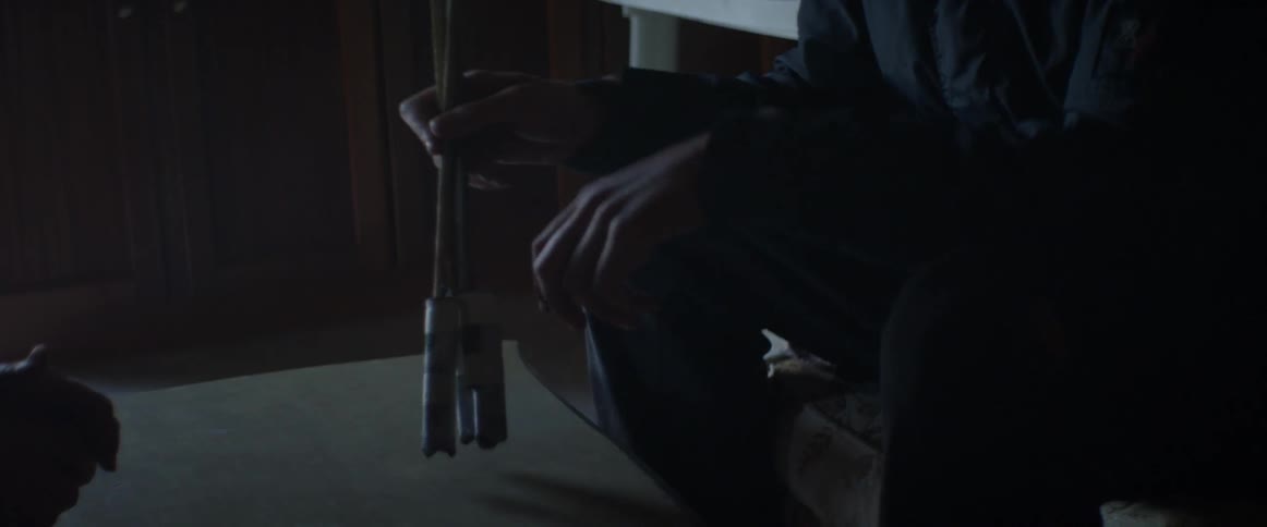 Man sitting in a dark room holding sticks