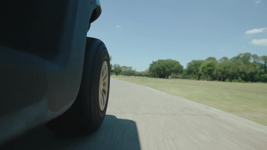 A golf cart drives down a path on a golf course