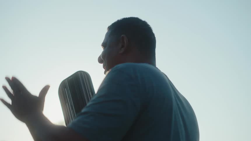 A man with a pickleball paddle gestures with his hands