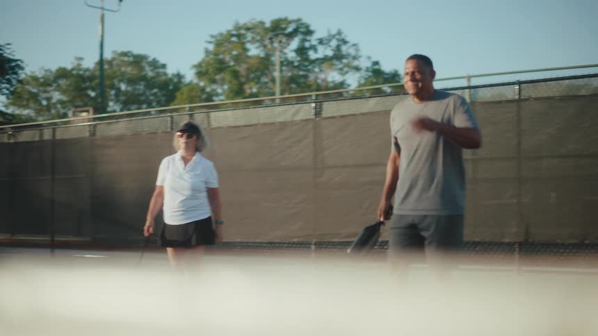 Man and woman side by side on a court playing pickleball