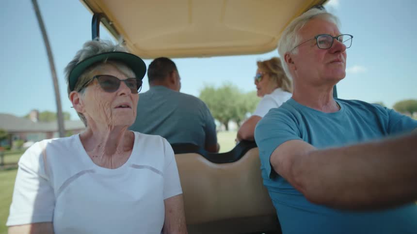 Four people in a golf cart moving through a natural environment