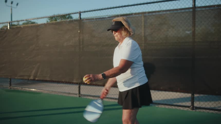 Elderly lady with a paddle playing pickleball