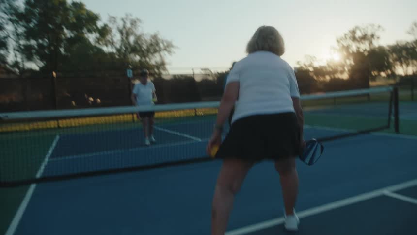 A group of elderly people practice volleying before a pickleball game