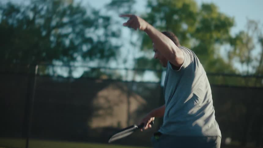 An elderly black man chases after a ball on a pickleball court