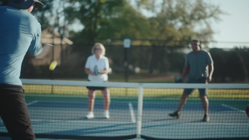Four individuals playing pickleball on an outdoor court