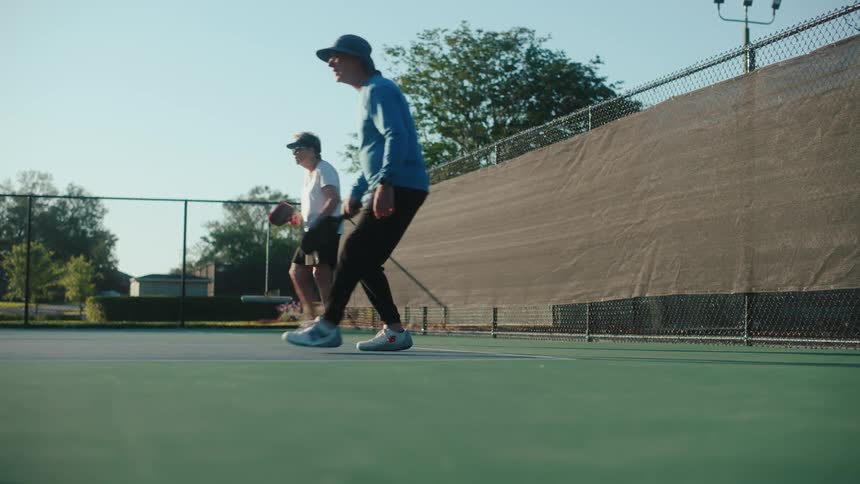 Two people in pairs on a court playing pickleball