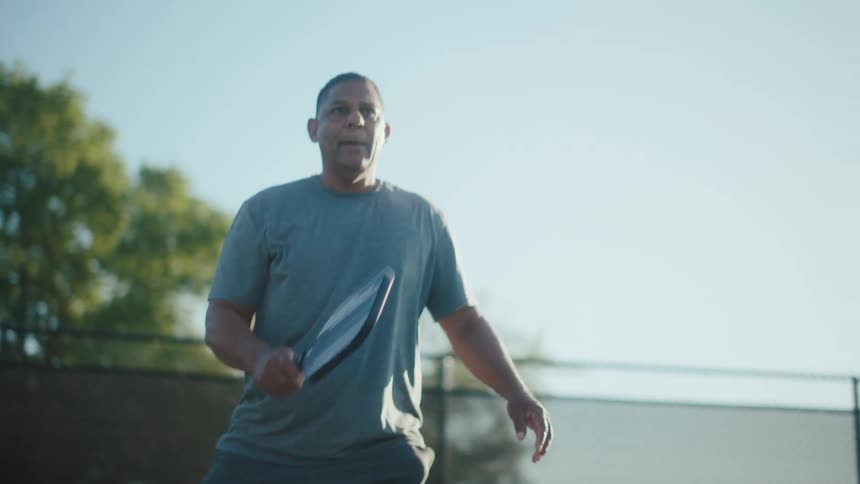Man on a court with a paddle playing pickleball